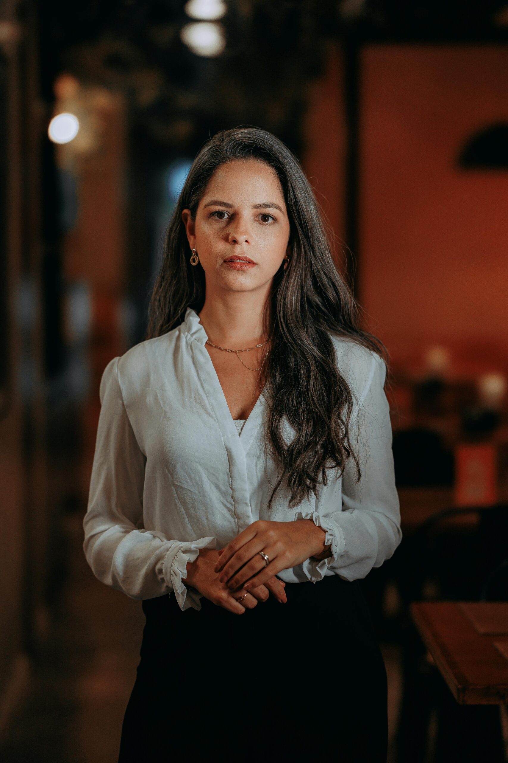 Confident young woman in business attire standing indoors, exuding professionalism.